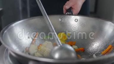 厨师用慢动作的热锅炒菜和鱼，煮亚洲锅，在热锅里搅拌，中国快餐